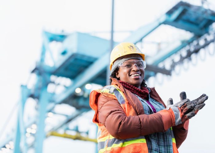 employee in hard hat and safety vest smling on a job site